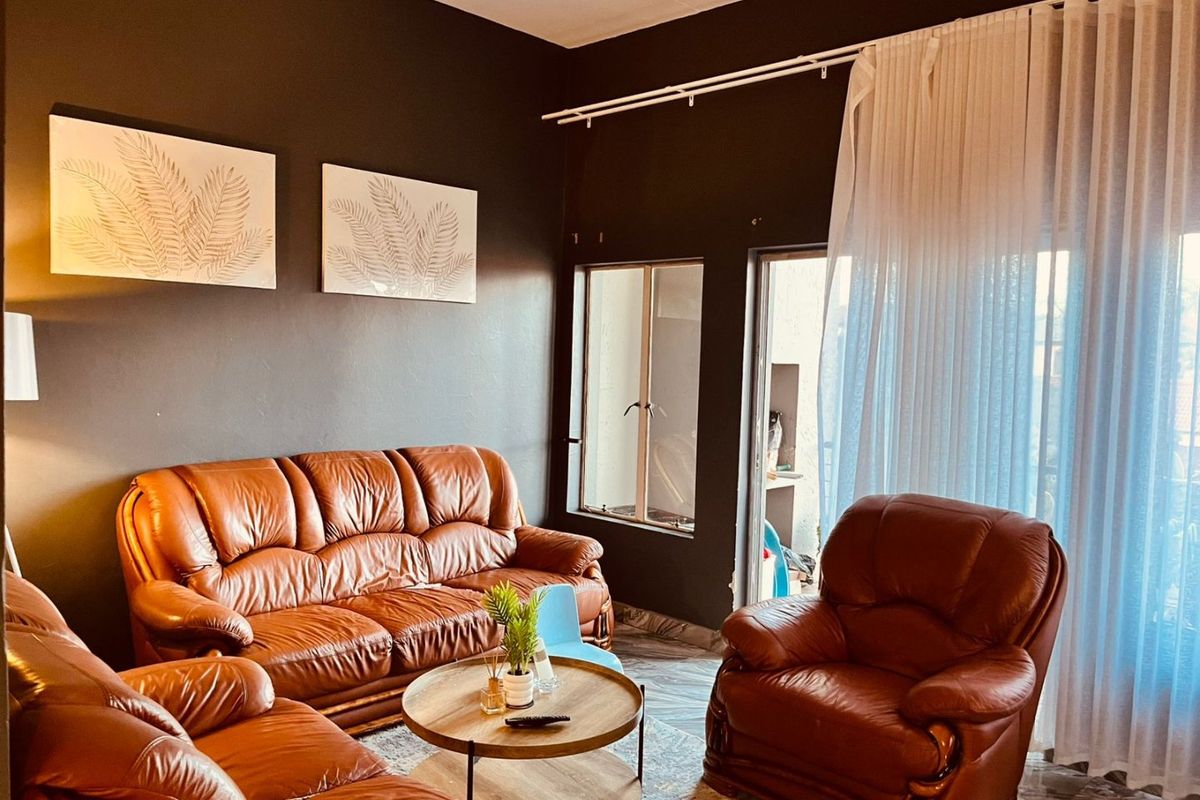 A living room featuring dark painted walls, tiled flooring, and a sliding glass door providing access to an outdoor area.