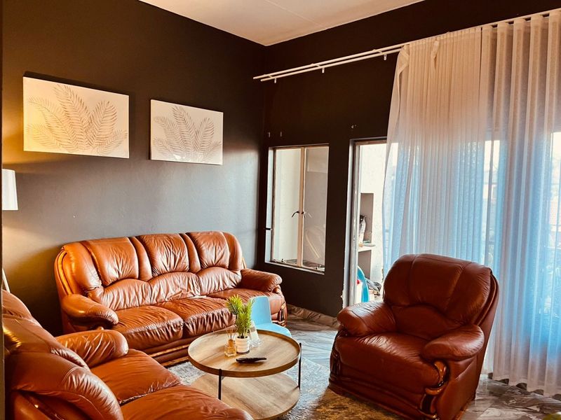 A living room featuring dark painted walls, tiled flooring, and a sliding glass door providing access to an outdoor area.