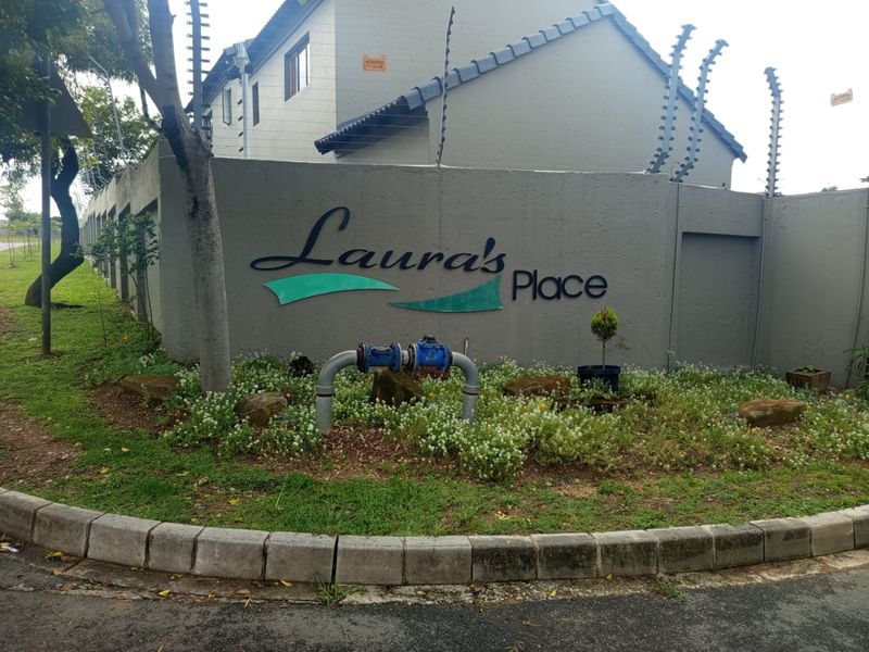 Exterior view of the Laura's Place complex entrance, featuring a perimeter wall with electric fencing and signage.