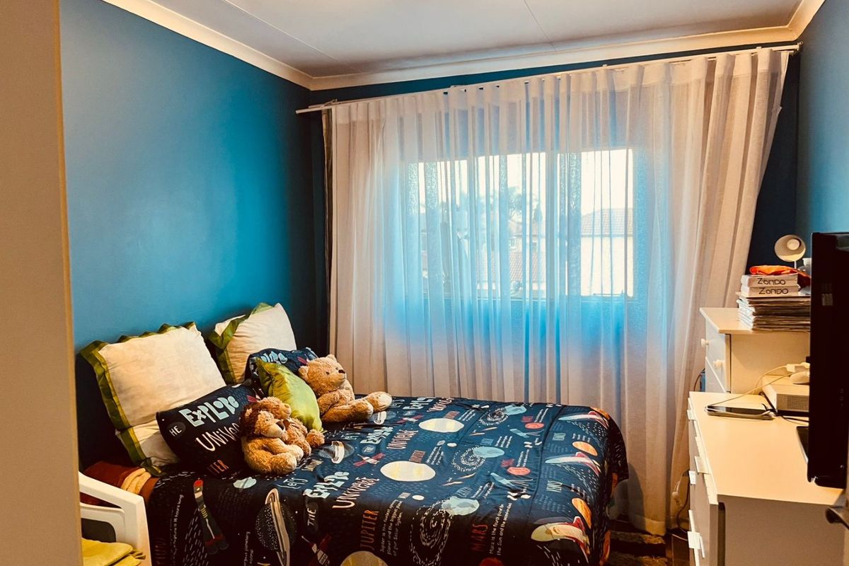 A bedroom featuring blue painted walls, a window with sheer curtains, and coving detail.