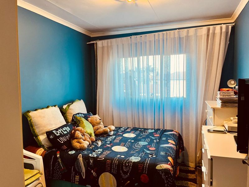 A bedroom featuring blue painted walls, a window with sheer curtains, and coving detail.