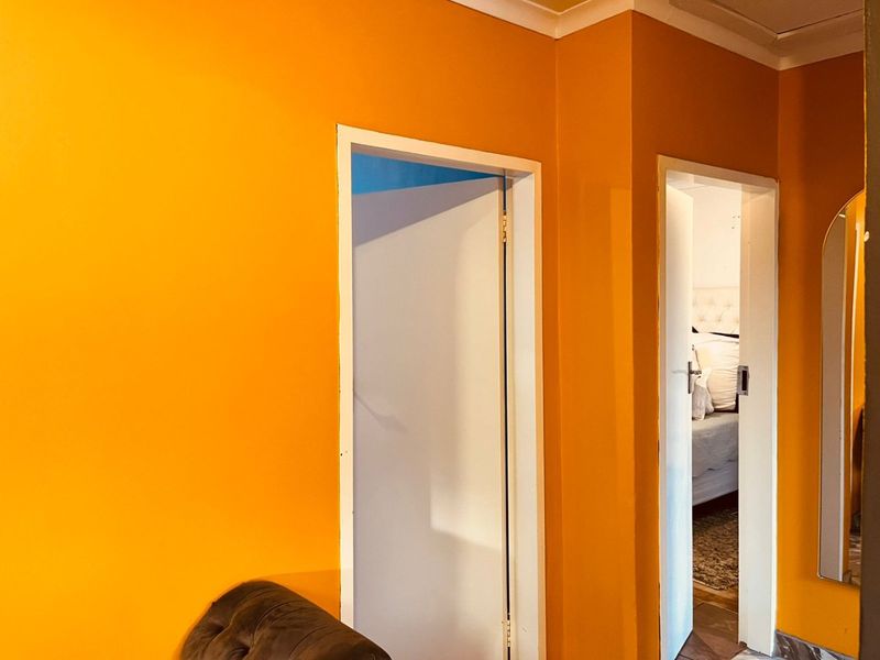 A hallway area featuring bright orange painted walls and access to adjacent rooms through standard door frames.