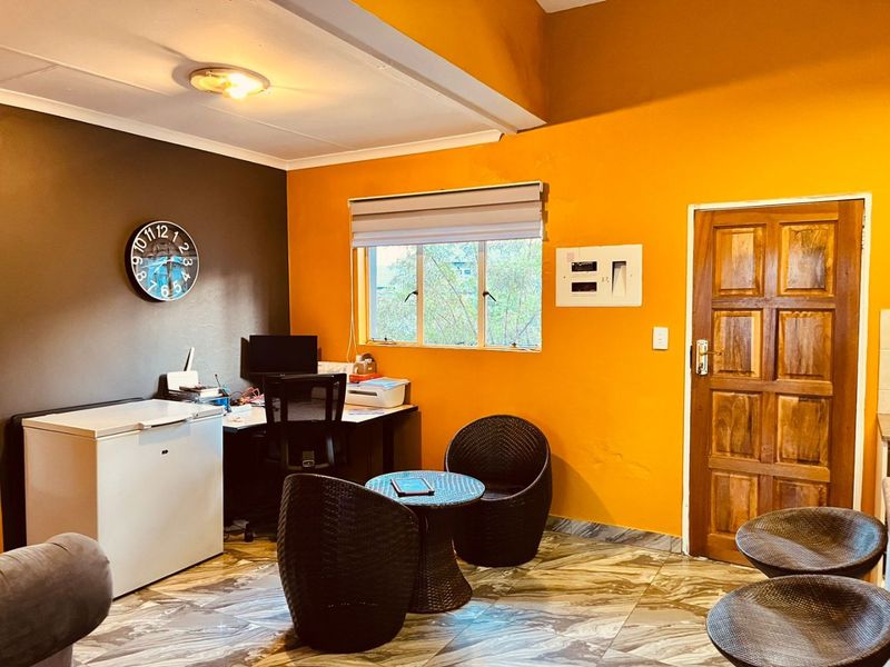 A multi-purpose living area featuring tiled flooring, a wooden door, and an integrated electrical distribution board on the wall.
