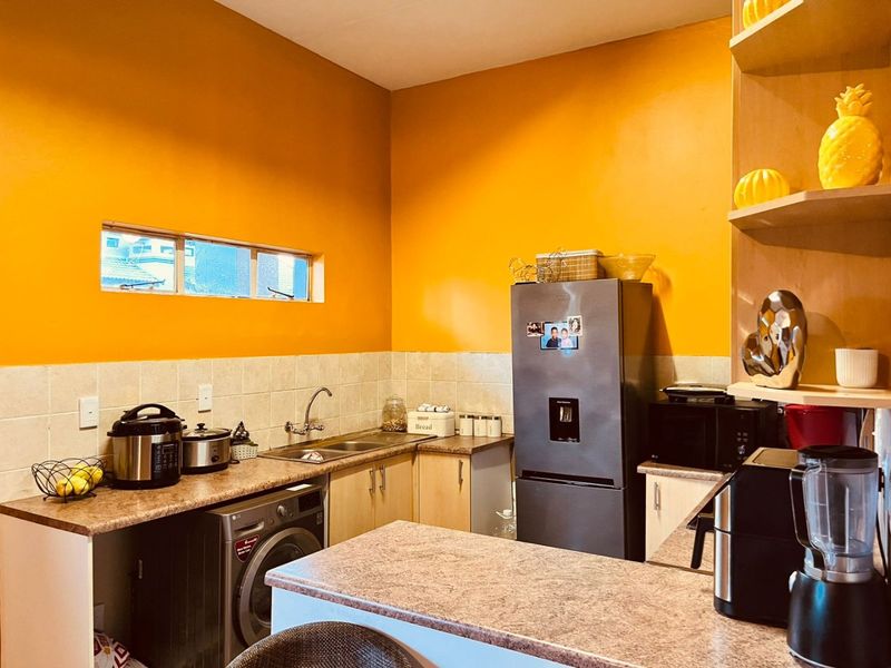 A functional kitchen featuring laminate countertops, tiled backsplash, built-in cabinetry, and integrated shelving, providing practical storage and workspace.