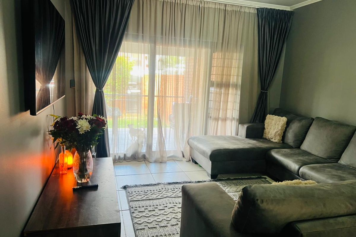 A comfortable living room featuring tiled flooring and a large sliding glass door that provides access to the outdoor area.