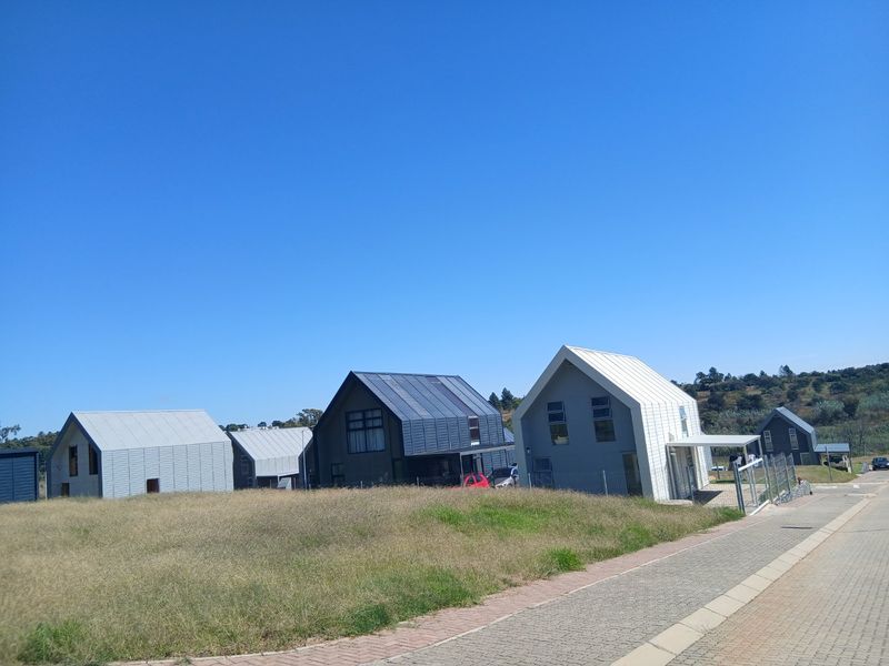 A street-level view of modern residential homes featuring pitched metal roofs and paved access paths in a suburban estate setting.