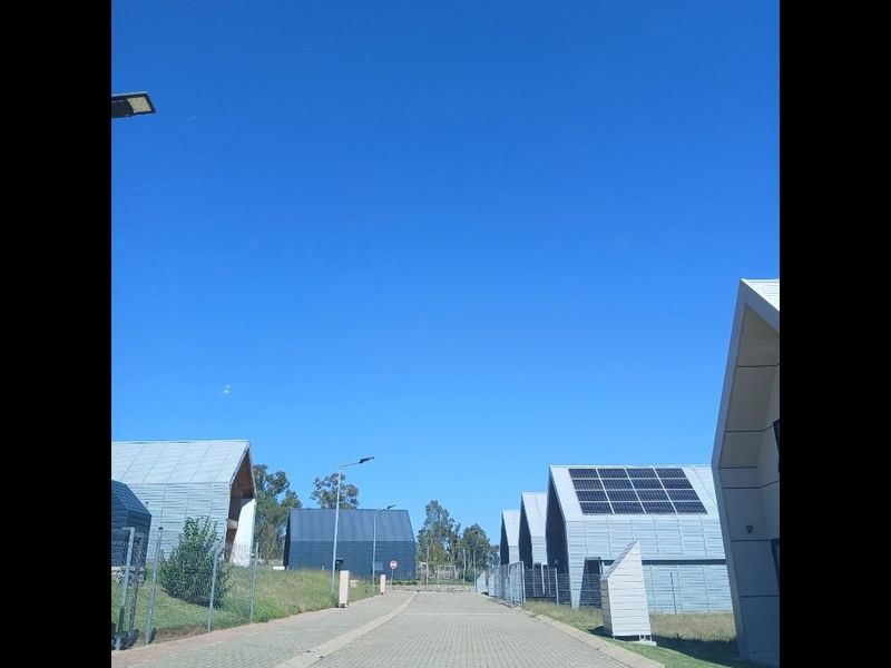 A view of a modern residential street featuring contemporary homes with pitched roofs, solar panels, and paved access roads.