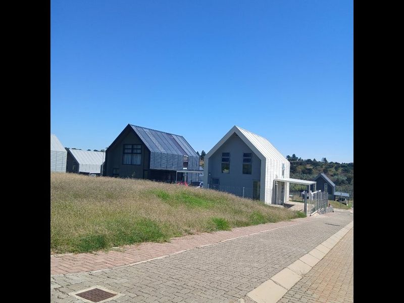 A street-level view of modern residential houses featuring gabled roofs and paved driveway access in a suburban estate setting.