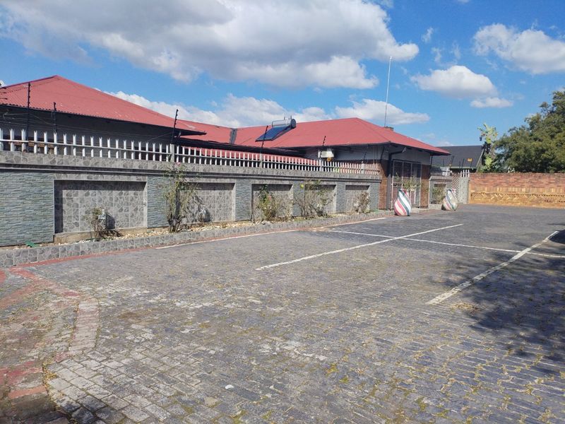 Spacious paved driveway leading to the front facade of the house, featuring a secure perimeter wall with electric fencing and a solar water heater.