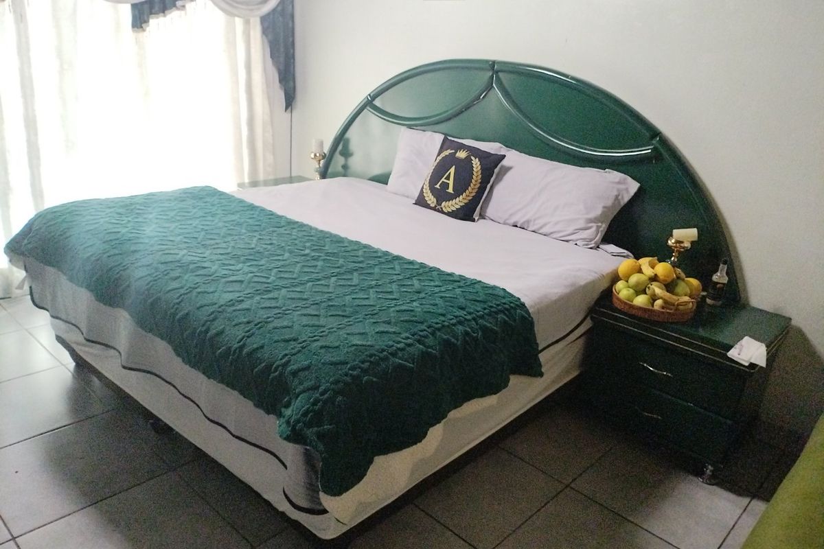 A bedroom featuring tiled flooring and a large window with curtain treatments.