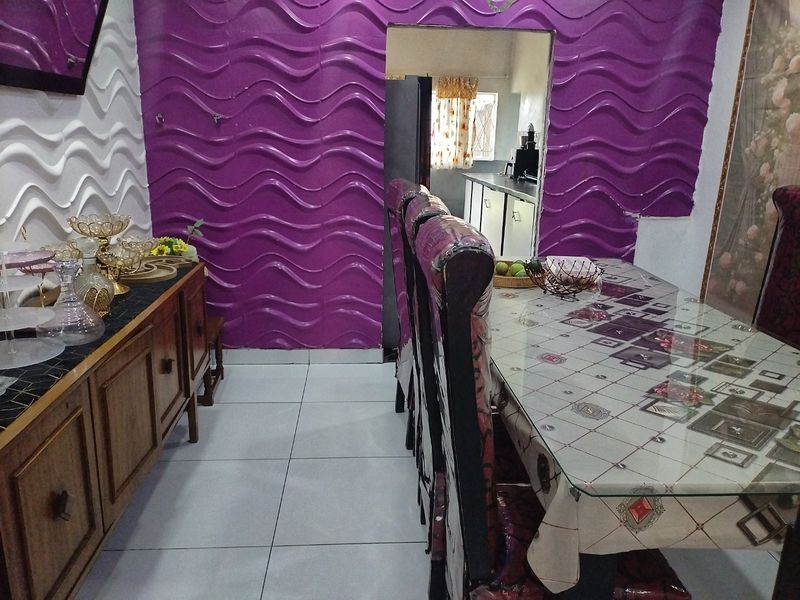 Dining area featuring distinctive textured wall panels and tiled flooring, with an open doorway leading to the kitchen space.