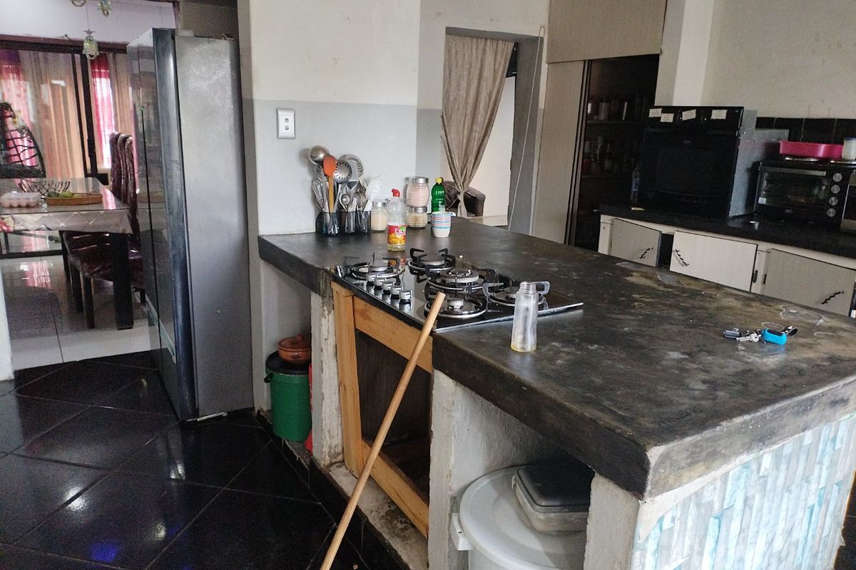 Kitchen area featuring a concrete island with a built-in gas hob, dark tiled flooring, and adjacent dining space access.