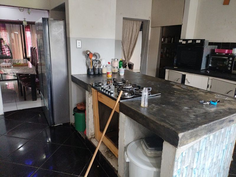 Kitchen area featuring a concrete island with a built-in gas hob, dark tiled flooring, and adjacent dining space access.