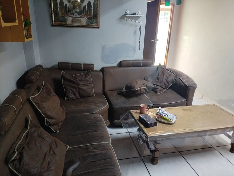 A living room area featuring tiled flooring and access to an adjacent space, showing signs of wear on the walls.