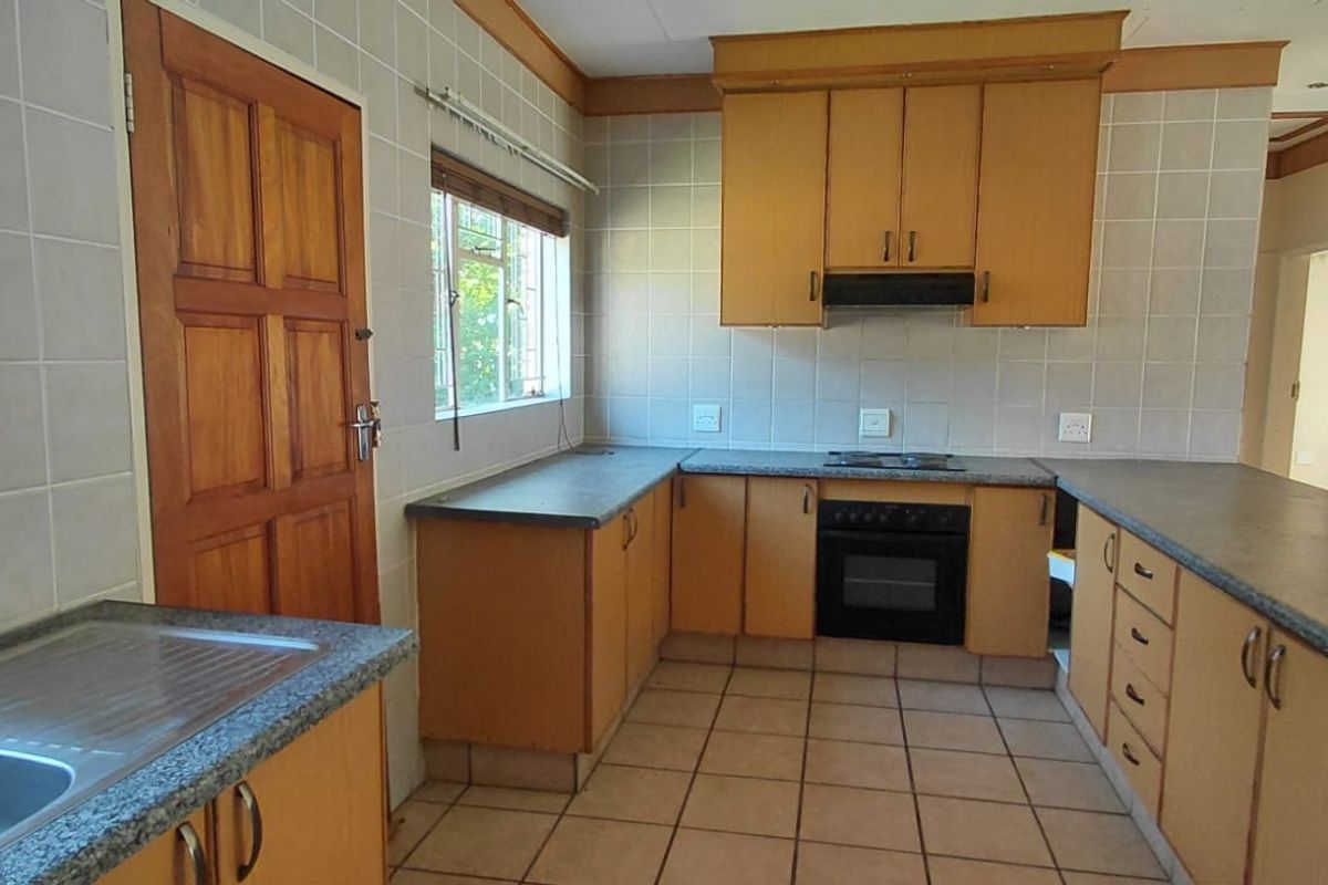 A functional kitchen featuring built-in cabinetry, laminate countertops, an integrated oven and hob, and tiled finishes throughout.