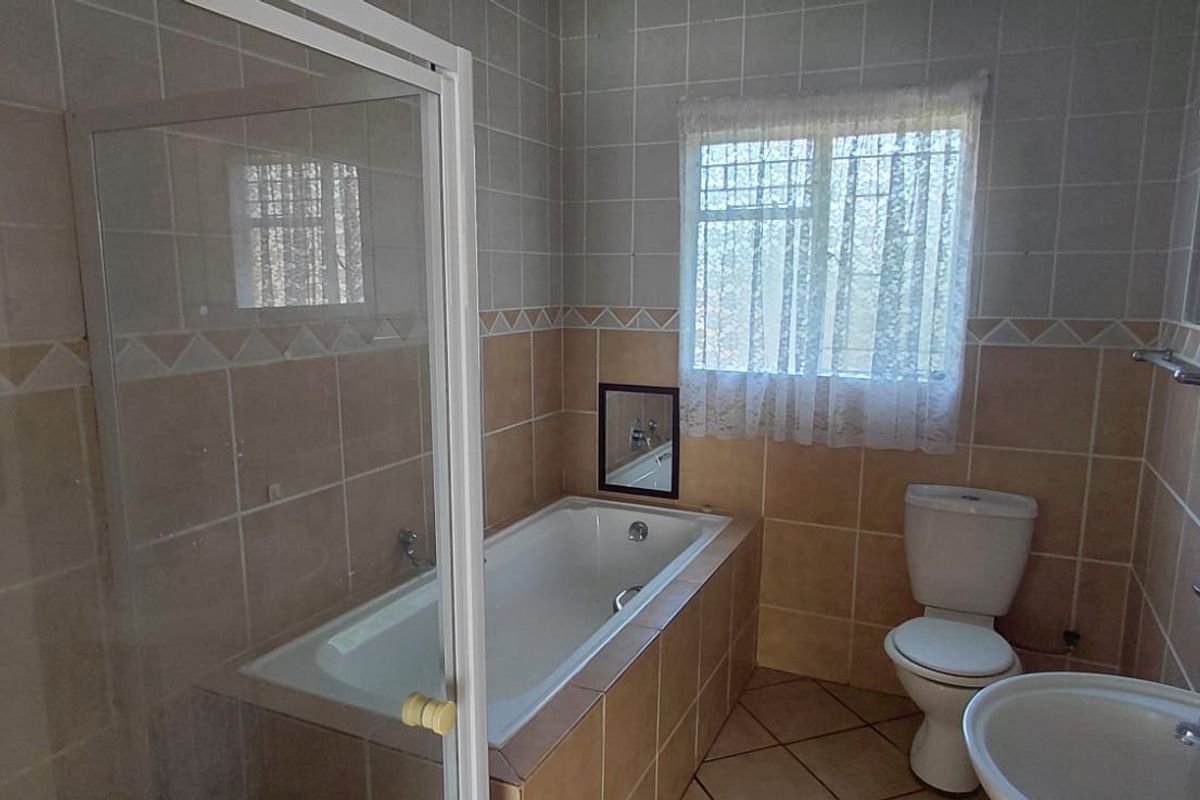 A functional bathroom featuring a built-in bathtub, separate shower enclosure, pedestal basin, and toilet with neutral ceramic wall and floor tiling.