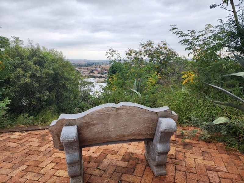 An outdoor area featuring brick paving and a stone bench, offering an elevated view of the surrounding landscape and neighborhood.