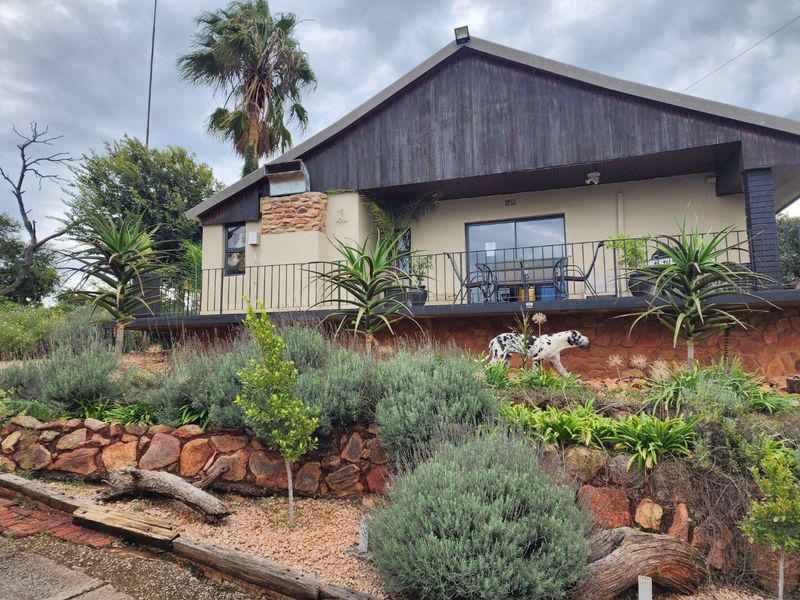 Rear elevation of a commercial property featuring a raised patio with metal balustrade, stone retaining walls, and timber-clad gable roof detail.