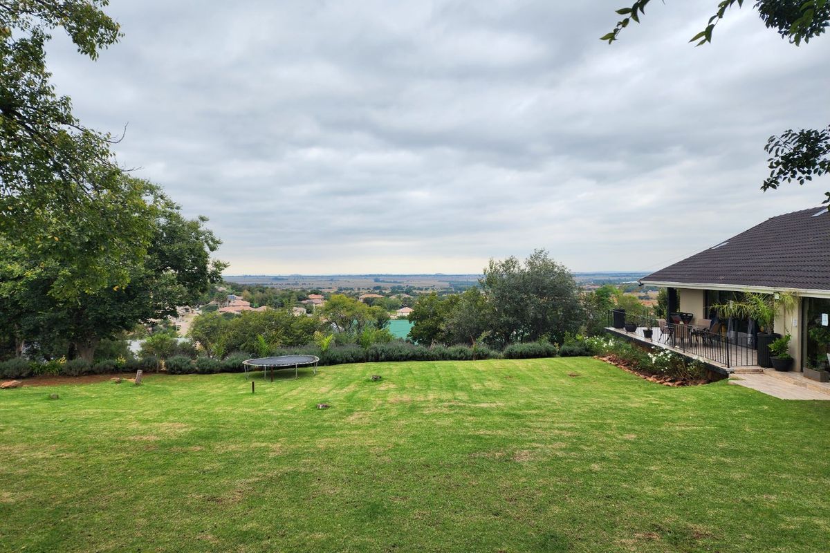 Spacious rear garden featuring a well-maintained lawn and an elevated patio area with scenic views of the surrounding landscape.