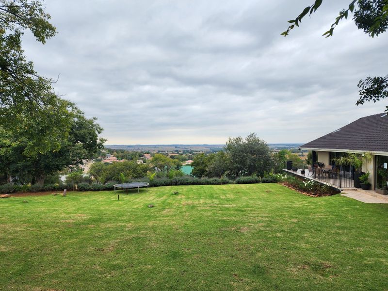 Spacious rear garden featuring a well-maintained lawn and an elevated patio area with scenic views of the surrounding landscape.