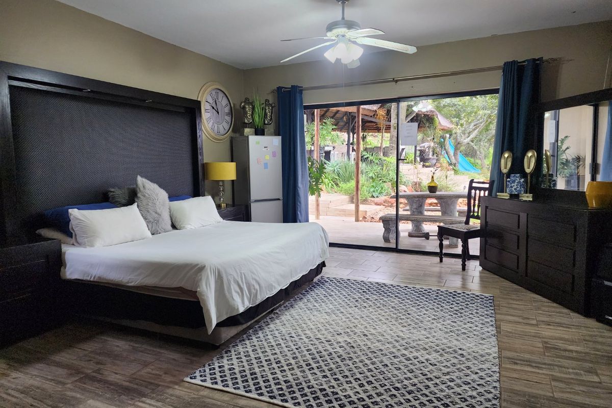 Spacious bedroom featuring tiled flooring, a ceiling fan, and large sliding glass doors providing direct access to the outdoor patio area.