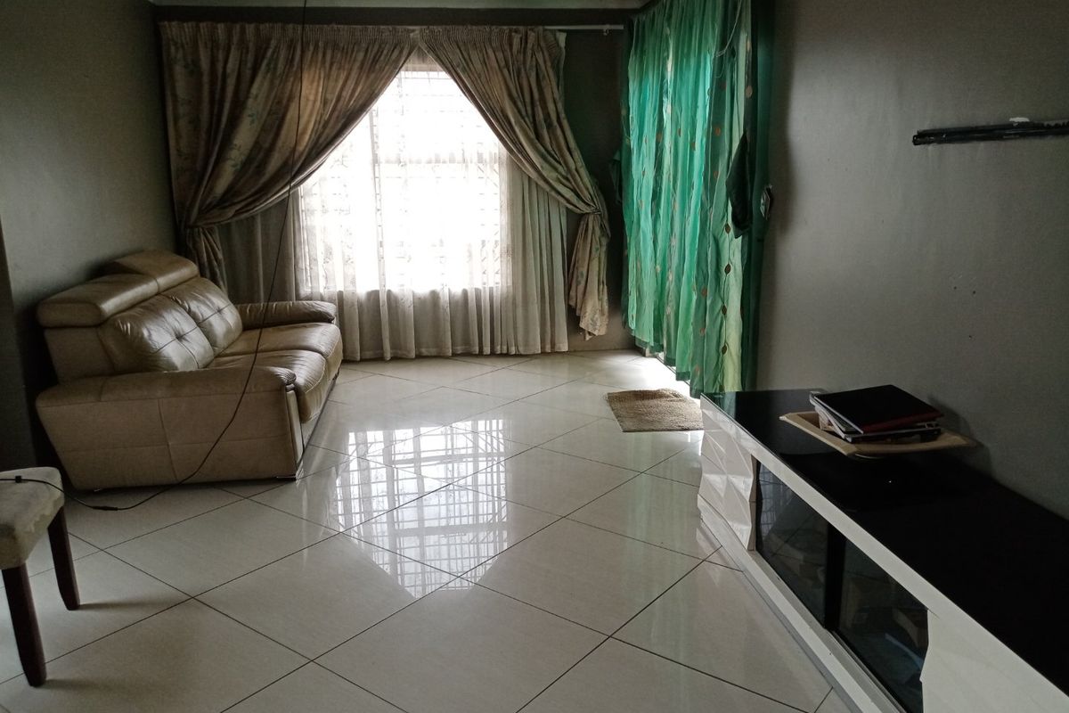 A living room featuring large format floor tiles, a sliding door leading outdoors, and window security bars.