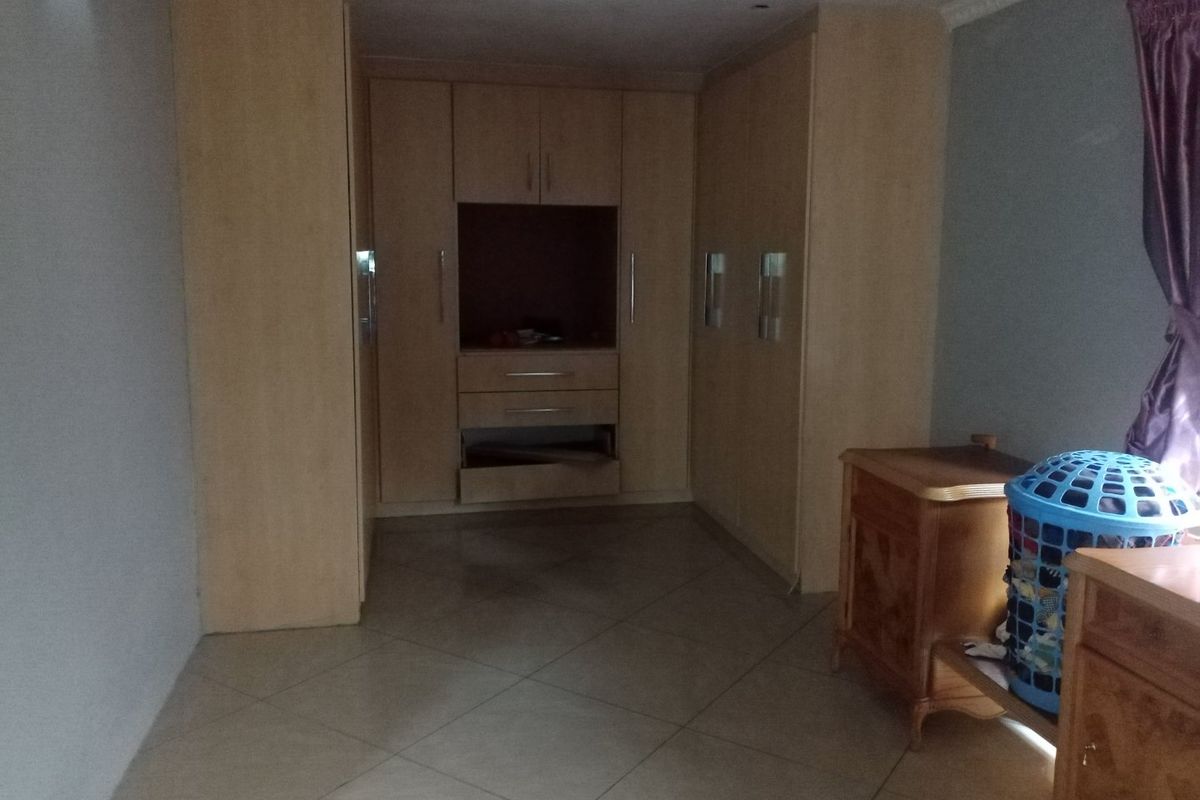 Bedroom featuring built-in wooden cupboards with integrated shelving and tiled flooring.