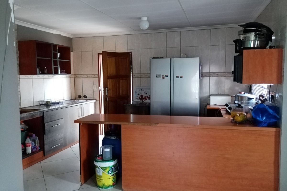 A functional kitchen featuring tiled walls, built-in cabinetry, and a breakfast bar, offering a practical layout with potential for cosmetic updates.