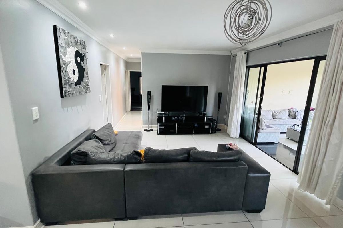Spacious living room featuring large format floor tiles, recessed lighting, and sliding glass doors providing seamless access to the outdoor patio area.