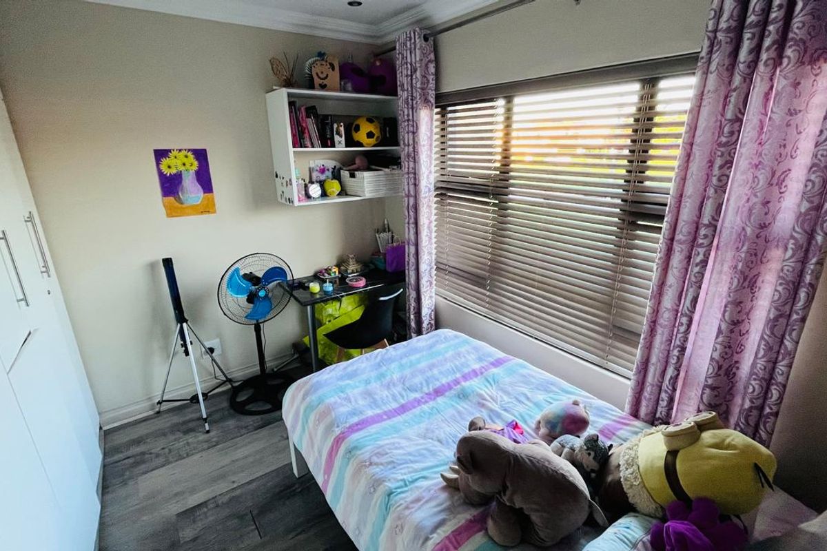A well-maintained bedroom featuring built-in cupboards, laminate flooring, and venetian blinds, offering a functional and comfortable living space.