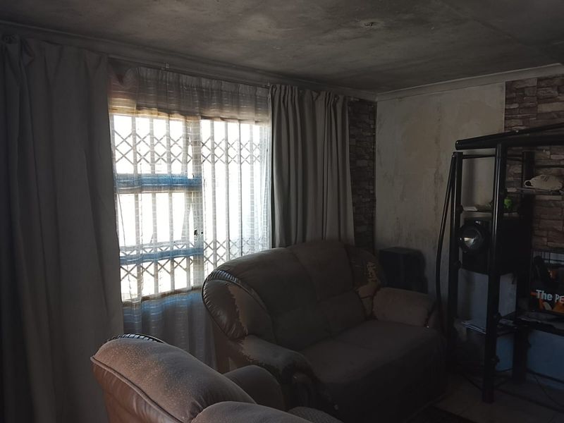 Living room featuring brick veneer accents, security gate, and visible ceiling and wall damage requiring maintenance and cosmetic repair.