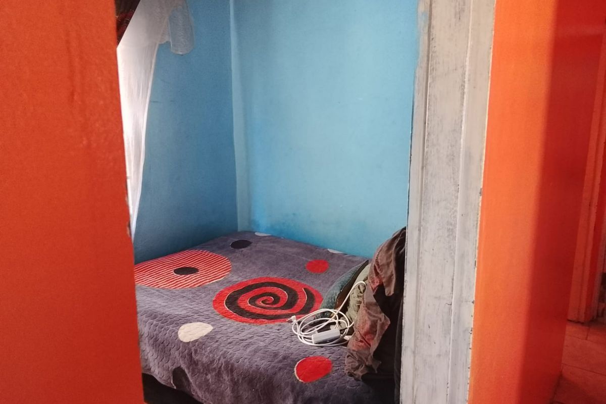 A small bedroom featuring blue painted walls and a wooden door frame, requiring cosmetic updates to improve the overall aesthetic and condition.