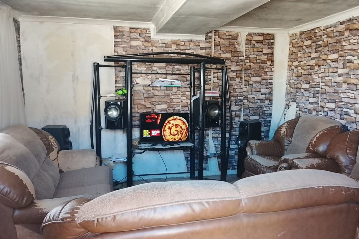 Living room featuring stone-effect wallpaper and coved ceiling, currently requiring significant cosmetic updates and wall repairs to improve the overall aesthetic.