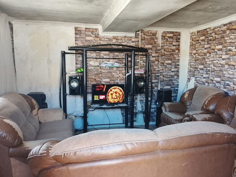 Living room featuring stone-effect wallpaper and coved ceiling, currently requiring significant cosmetic updates and wall repairs to improve the overall aesthetic.