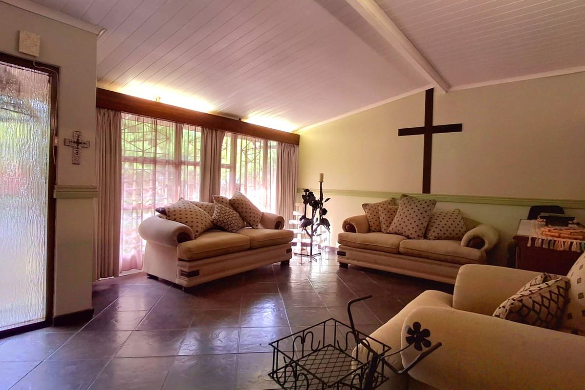 A spacious living room featuring tiled flooring, a timber-look ceiling, and large windows that provide ample natural light.