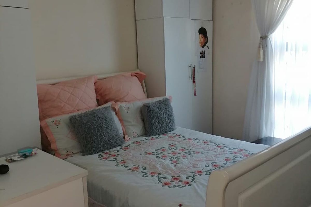 A functional bedroom featuring built-in white cabinetry and a window with sheer curtains, providing a practical and well-lit sleeping space.