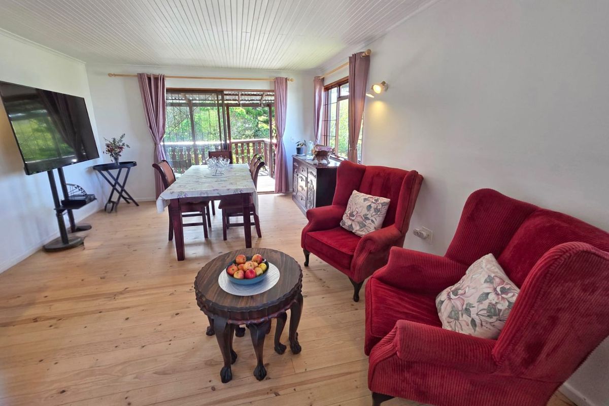 A bright living and dining area featuring light timber flooring, tongue and groove ceiling, and sliding glass doors leading to an outdoor balcony.