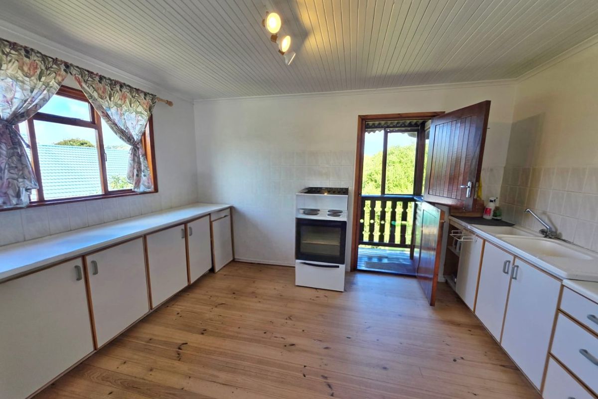 A functional kitchen featuring timber flooring, tongue and groove ceiling, built-in cabinetry, and a stable door leading to an outdoor area.