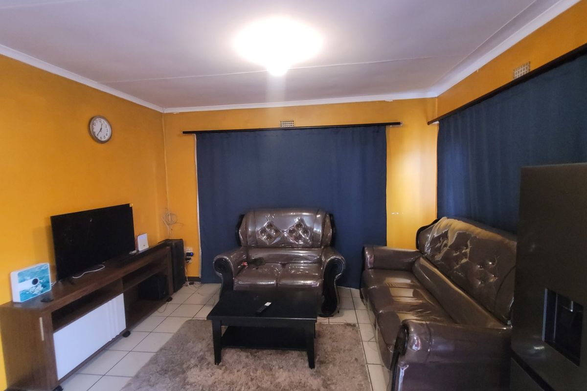 A living room featuring tiled flooring and curtain rails, providing a functional space for relaxation.