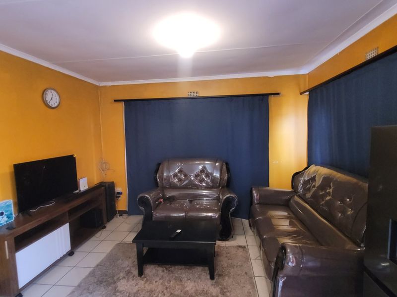 A living room featuring tiled flooring and curtain rails, providing a functional space for relaxation.