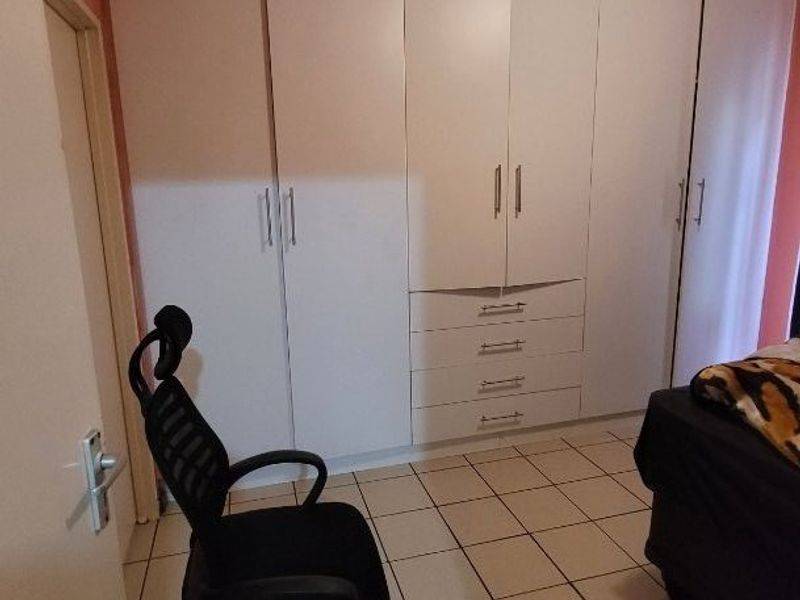 Bedroom featuring white built-in cupboards and tiled flooring.