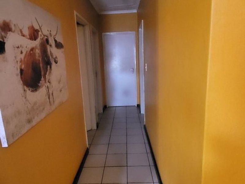 A functional hallway featuring tiled flooring and access to multiple rooms, finished with bright yellow wall paint.