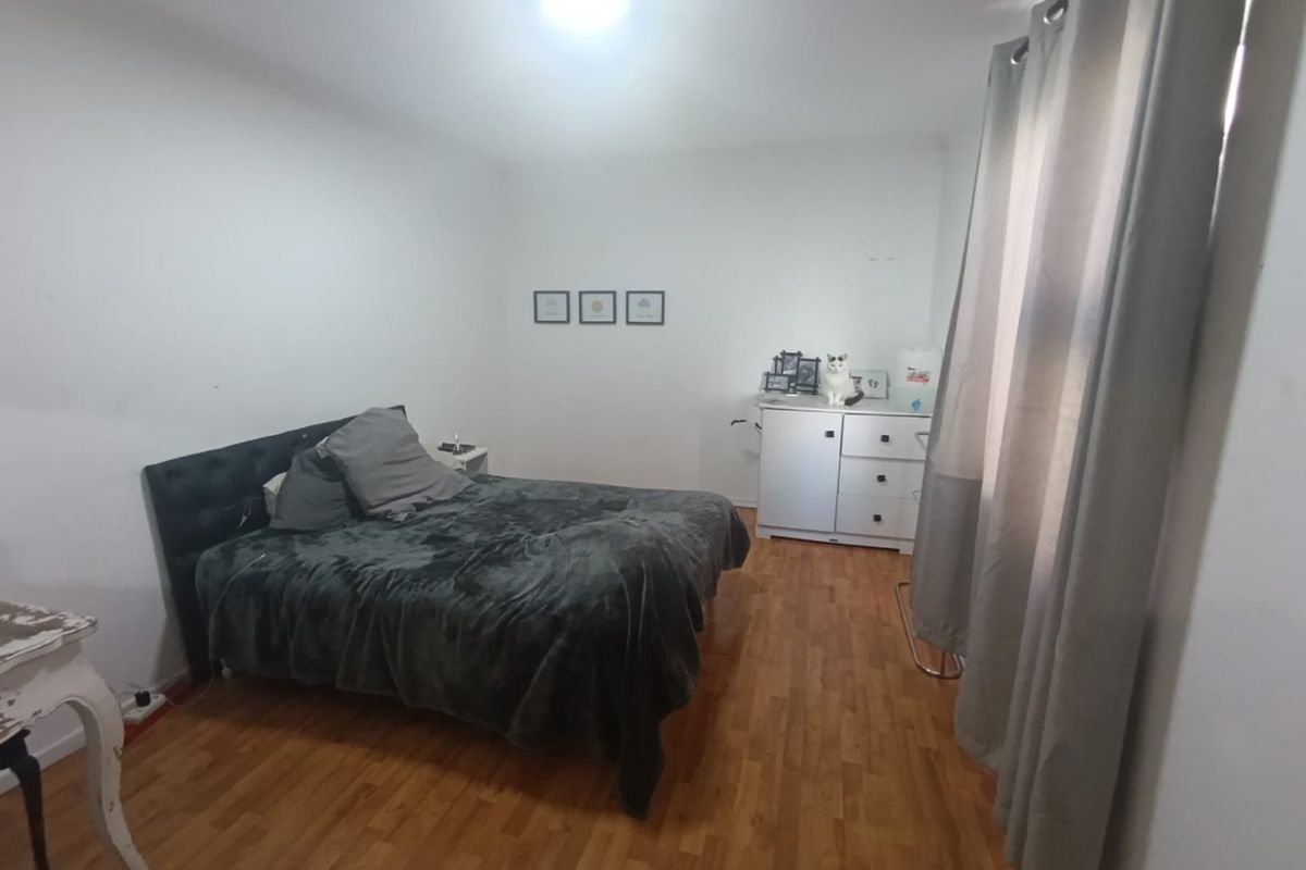 A functional bedroom featuring laminate flooring and neutral wall finishes, providing a blank canvas for personalization.
