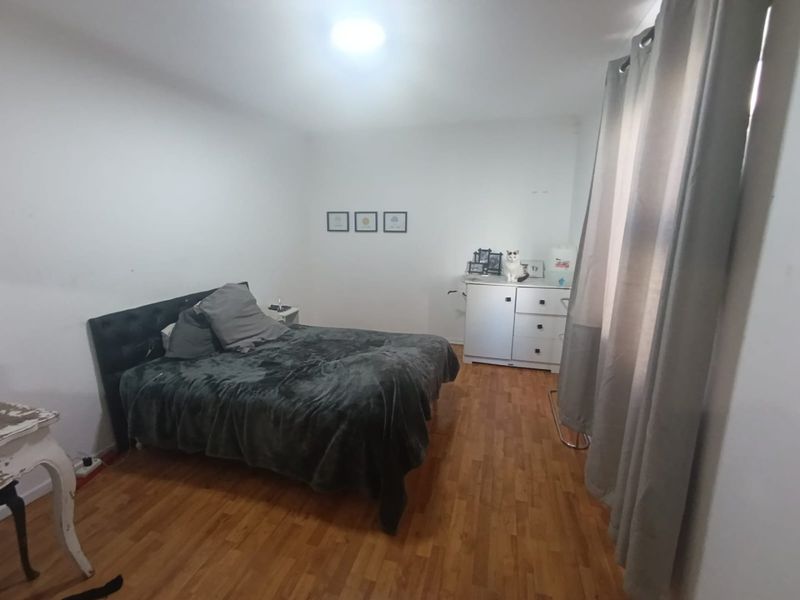 A functional bedroom featuring laminate flooring and neutral wall finishes, providing a blank canvas for personalization.