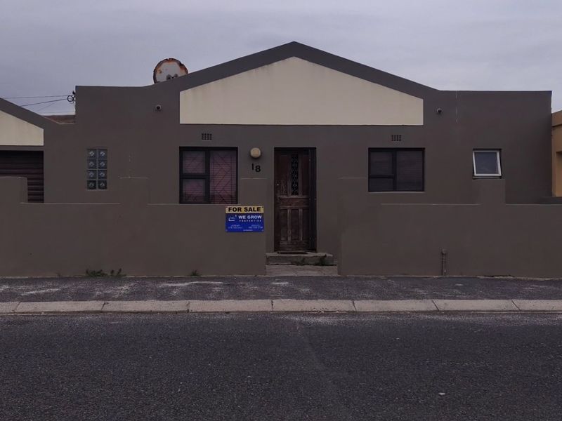 Front elevation of a single-story residential property featuring a garage, boundary wall, and street-facing entrance.