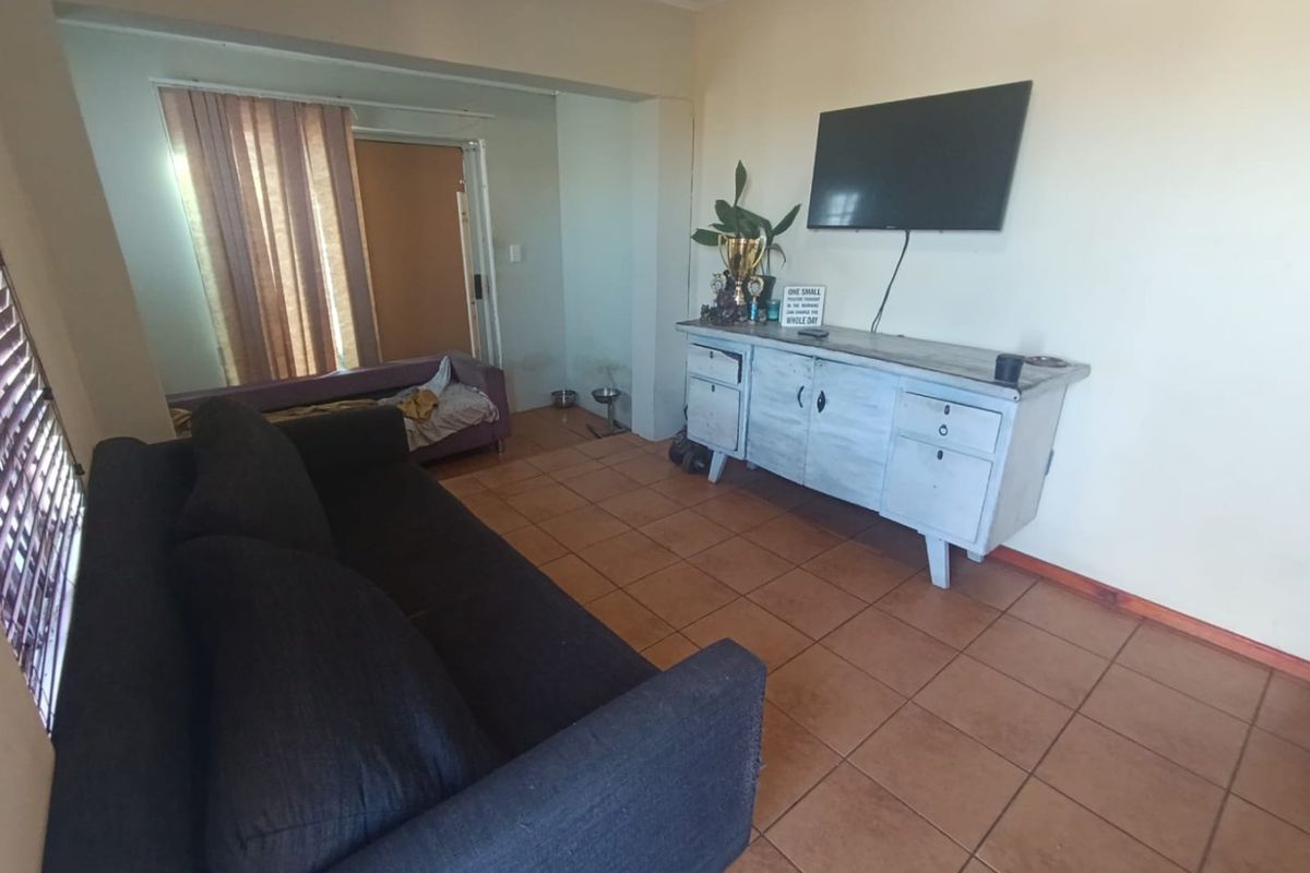 A living room featuring tiled flooring and cove cornicing, offering a functional space with potential for cosmetic updates to enhance its appeal.