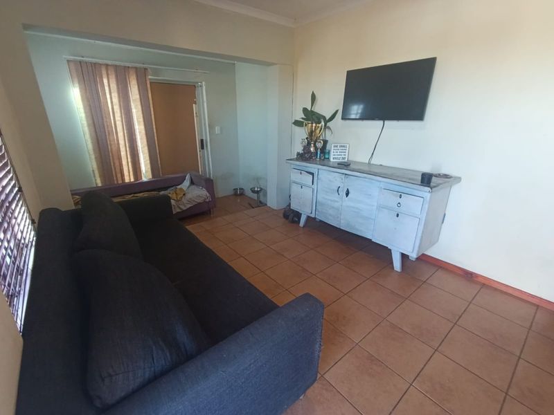 A living room featuring tiled flooring and cove cornicing, offering a functional space with potential for cosmetic updates to enhance its appeal.