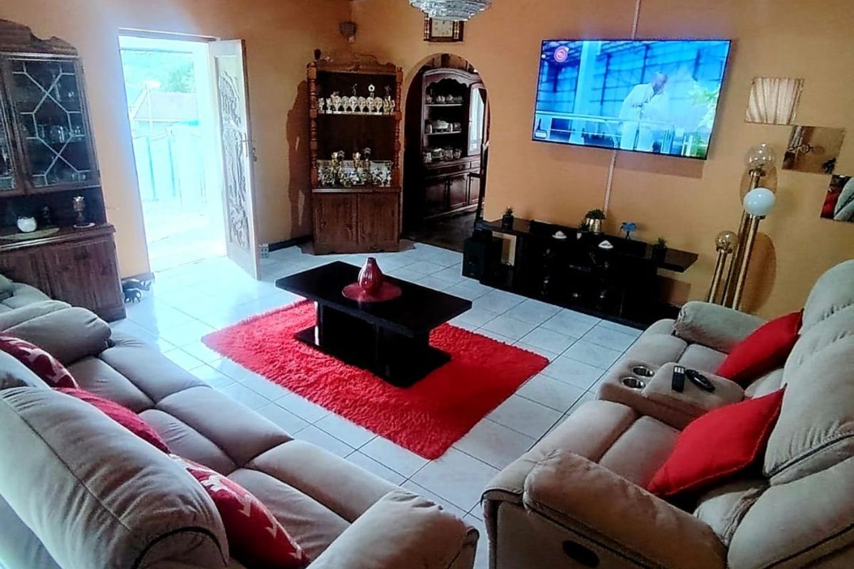A living room featuring a timber tongue and groove ceiling, tiled flooring, and an arched doorway leading to an adjacent space.
