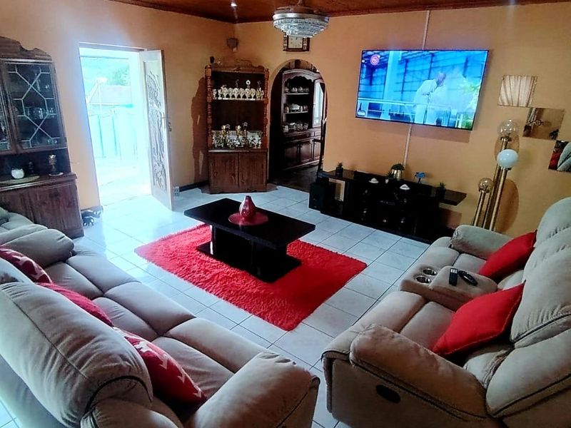 A living room featuring a timber tongue and groove ceiling, tiled flooring, and an arched doorway leading to an adjacent space.
