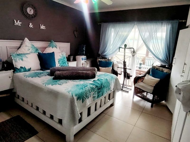 A bedroom featuring tiled flooring, a ceiling fan, and a sliding glass door providing access to an outdoor area.